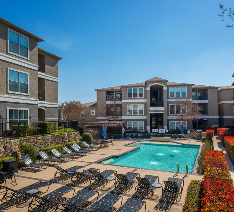 Swimming pool area with fountains and chaise lounge chairs at Vail Quarters in Dallas, Texas