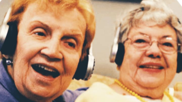 Two residents wearing headphones at  Quail Park Memory Care Residences of West Seattle
