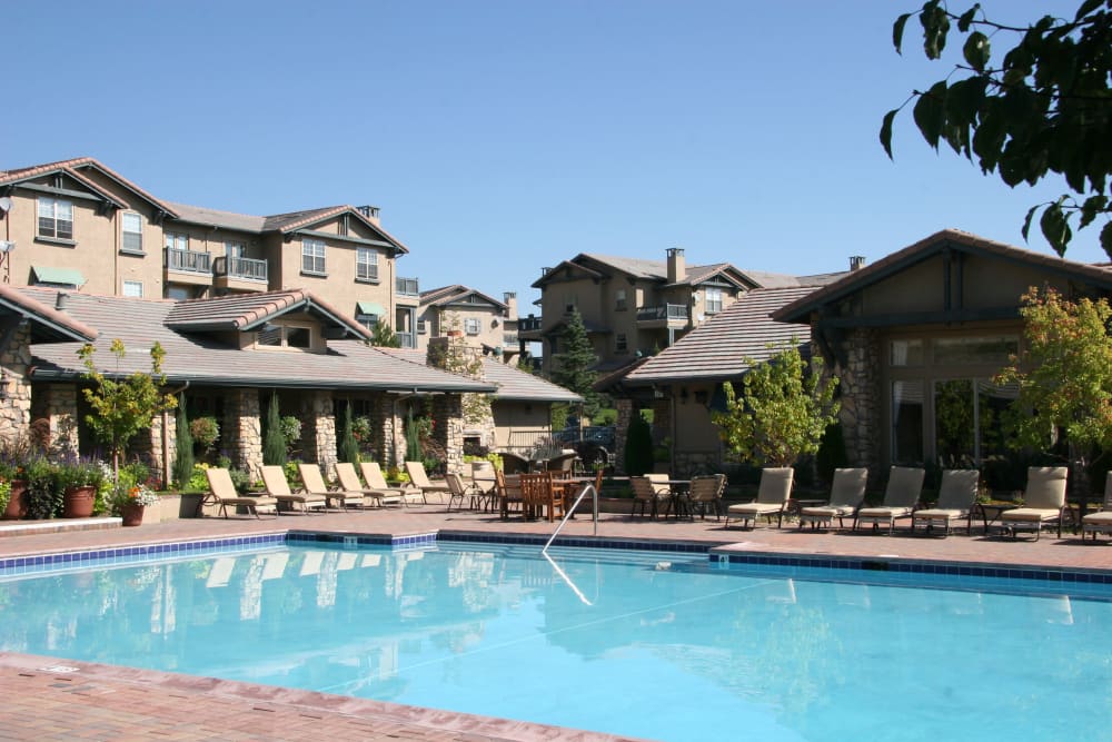 Sparkling swimming pool with plenty of poolside lounge seating at Montrachet Apartment Homes in Lakewood, Colorado