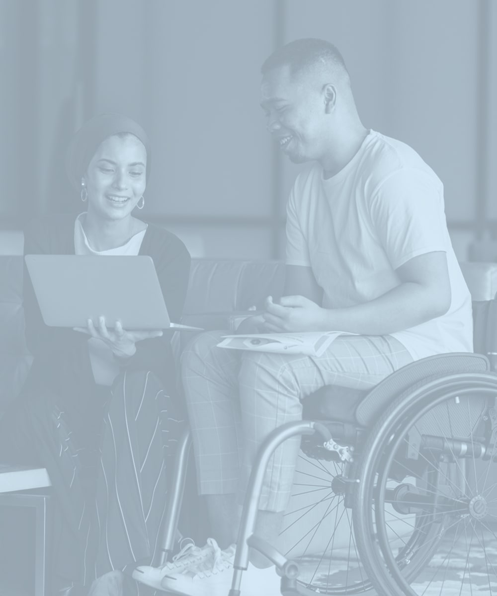 A woman with a laptop computer helps a man in a wheel chair Decron Properties, Los Angeles, California