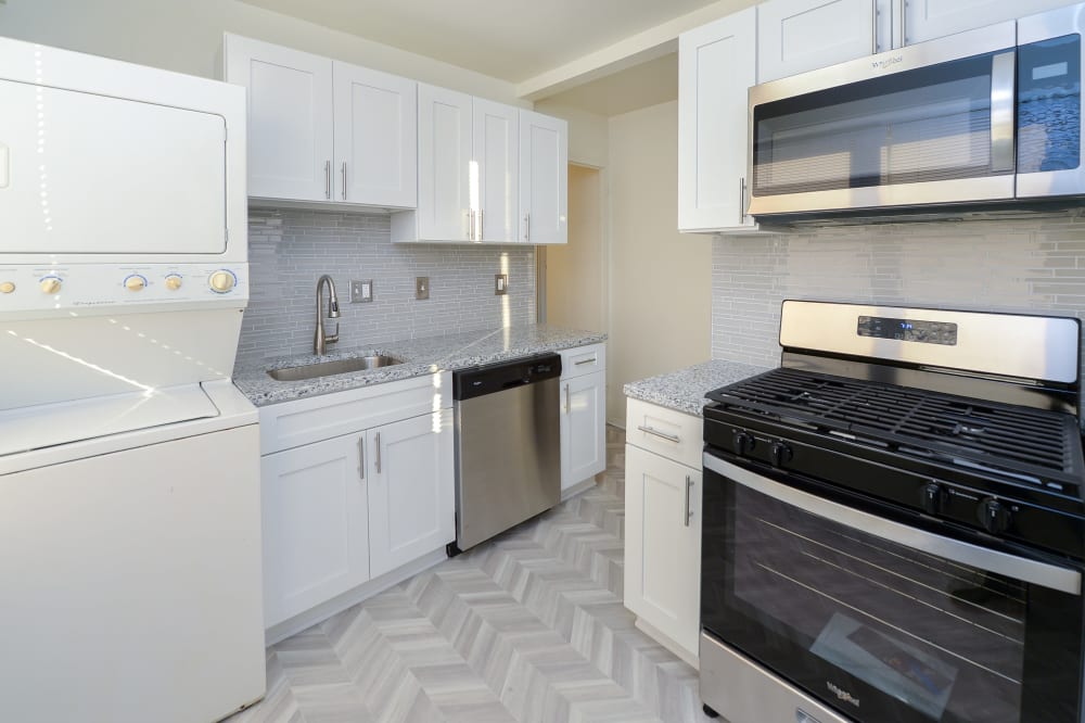 Renovated kitchen with white cabinets, granite countertops, and in-unit laundry