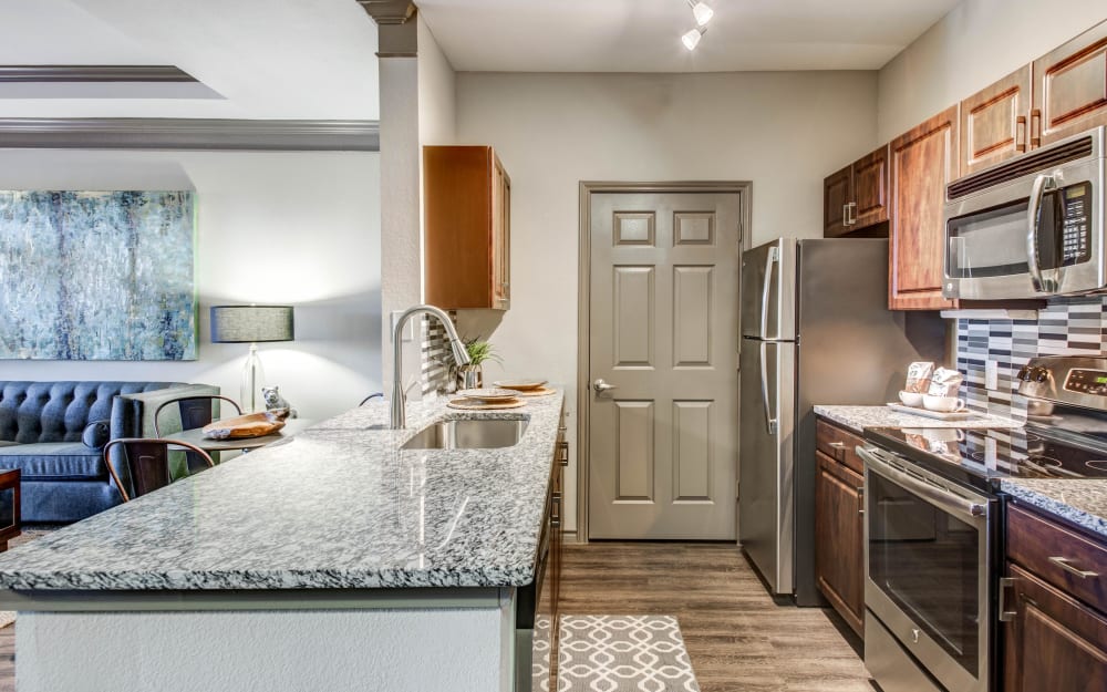 Granite countertops and tile backsplash in model home's kitchen at Beck at Wells Branch in Austin, Texas