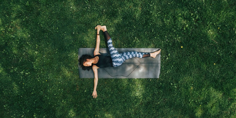 Resident doing yoga in a park near Tides at Meadowbrook in Fort Worth, Texas