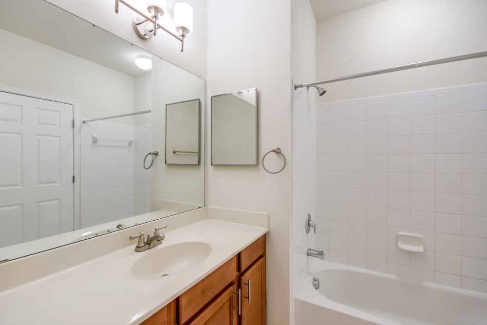 A west floor plan bathroom with large vanity mirrors at Manassas Station Apartments in Manassas, Virginia