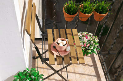 patio chair with coffee in a pink mug next to potted plants