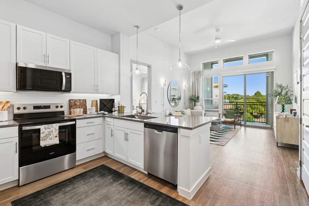 View of kitchen with living room in the background at Ennova Highlands in Arlington, Texas