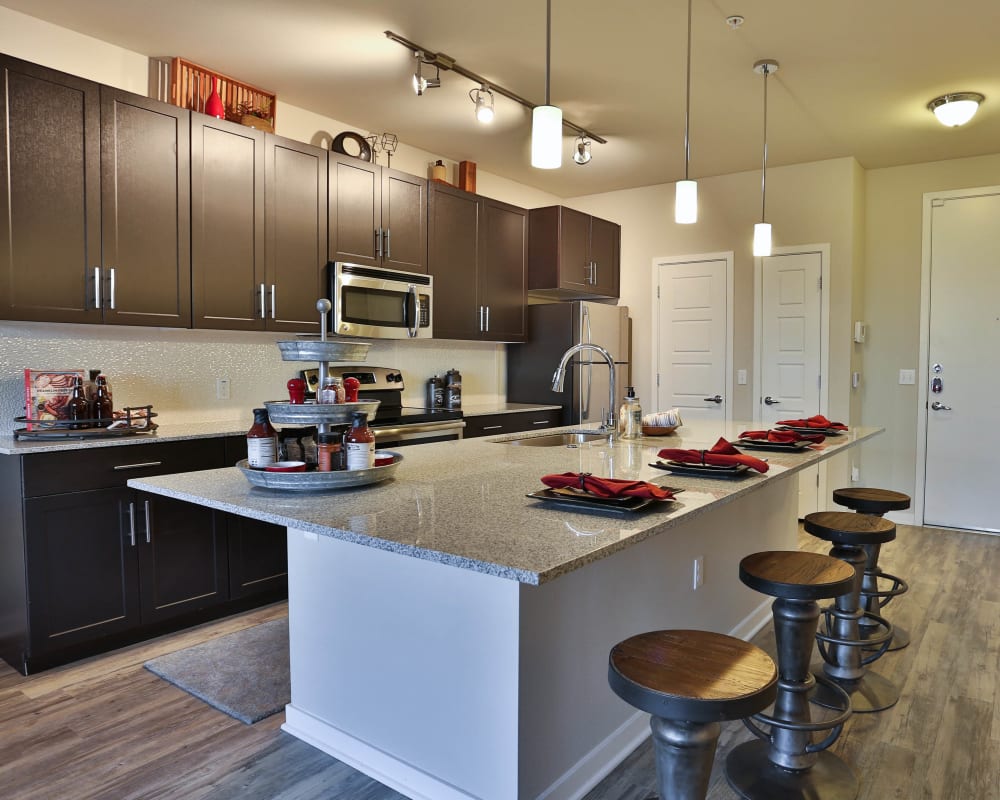 Rich, dark wood cabinetry and granite countertops in a model home's gourmet kitchen at Olympus Steelyard in Chandler, Arizona
