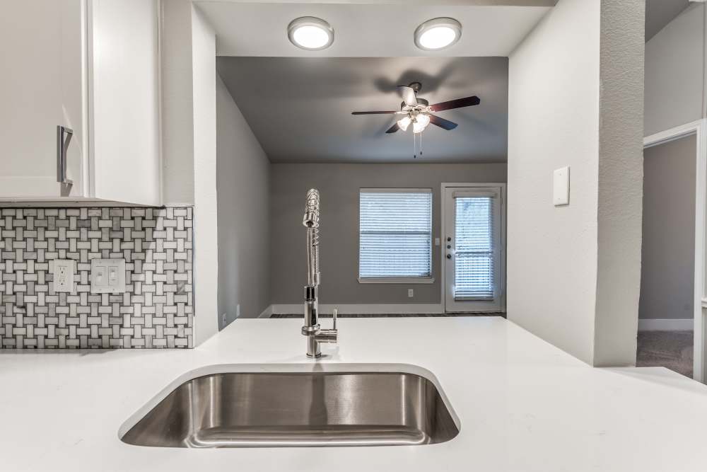 Kitchen with single sink and view to unfurnished living room at The Biltmore in The Woodlands, Texas