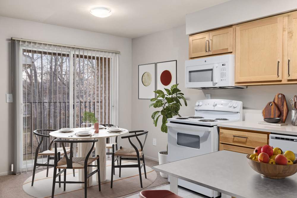 Dining room and living room opening onto a private patio at Farmington Oaks Apartments in Farmington, Michigan