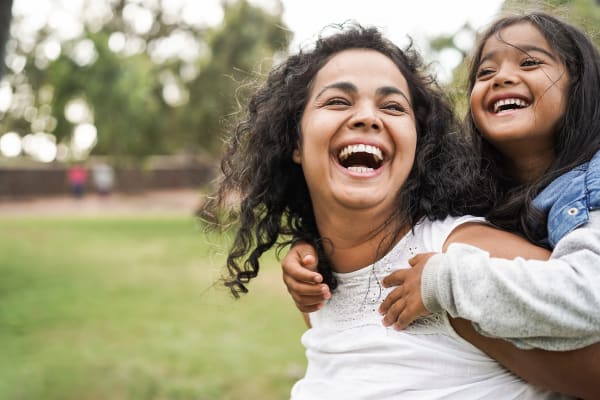 A mother smiling and holding her daughter on her back outside near The Station at Clift Farm in Madison, Alabama