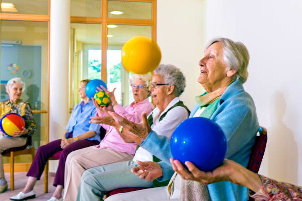 Residents in common area playing with colored balls for exercise 