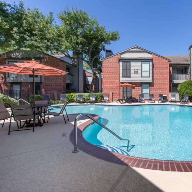 Swimming pool with umbrella covered table and chairs at Finley West in Houston, Texas