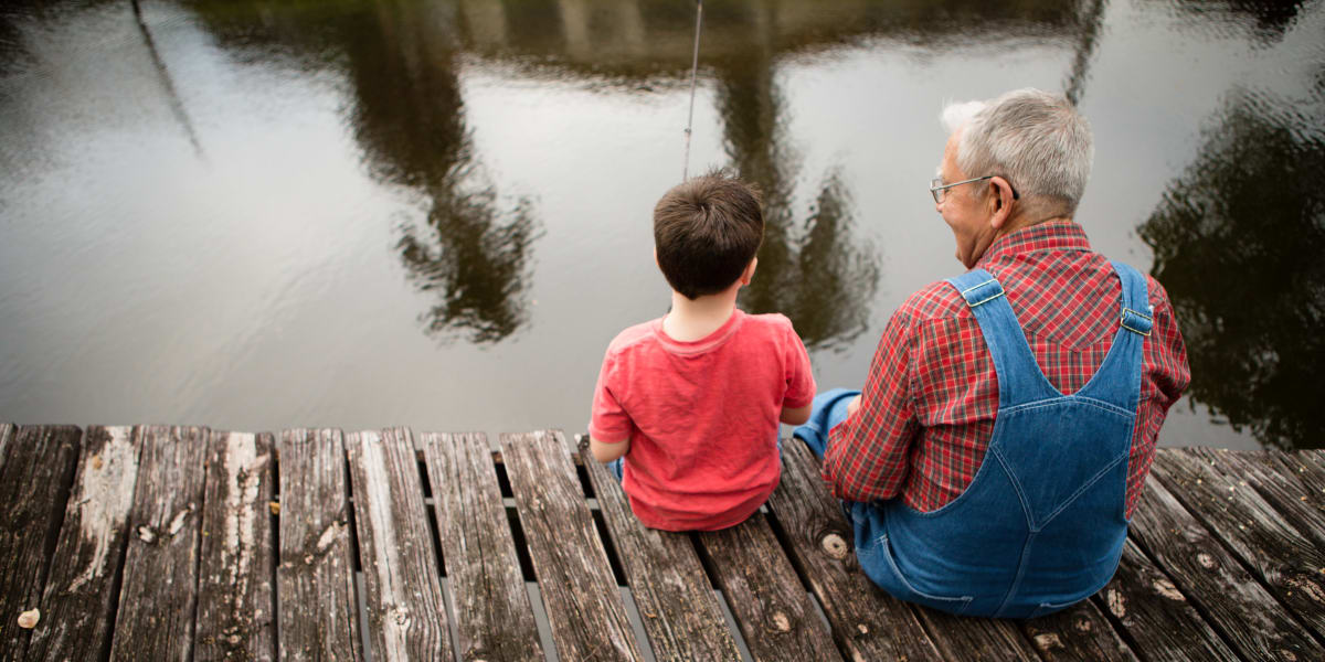 Resident sitting with a young family member on a dock at Hillcrest of Loveland in Loveland, Colorado