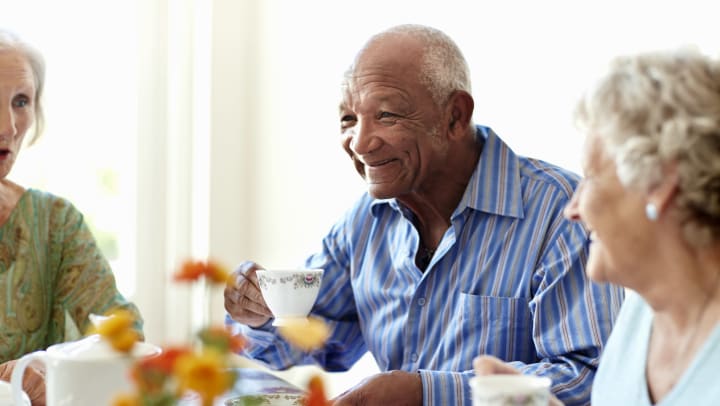 Elderly man having tea with senior ladies
