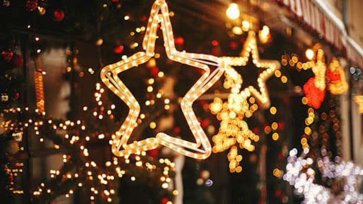 Golden star illumination and fir branches with red and gold baubles, golden lights in front of a building