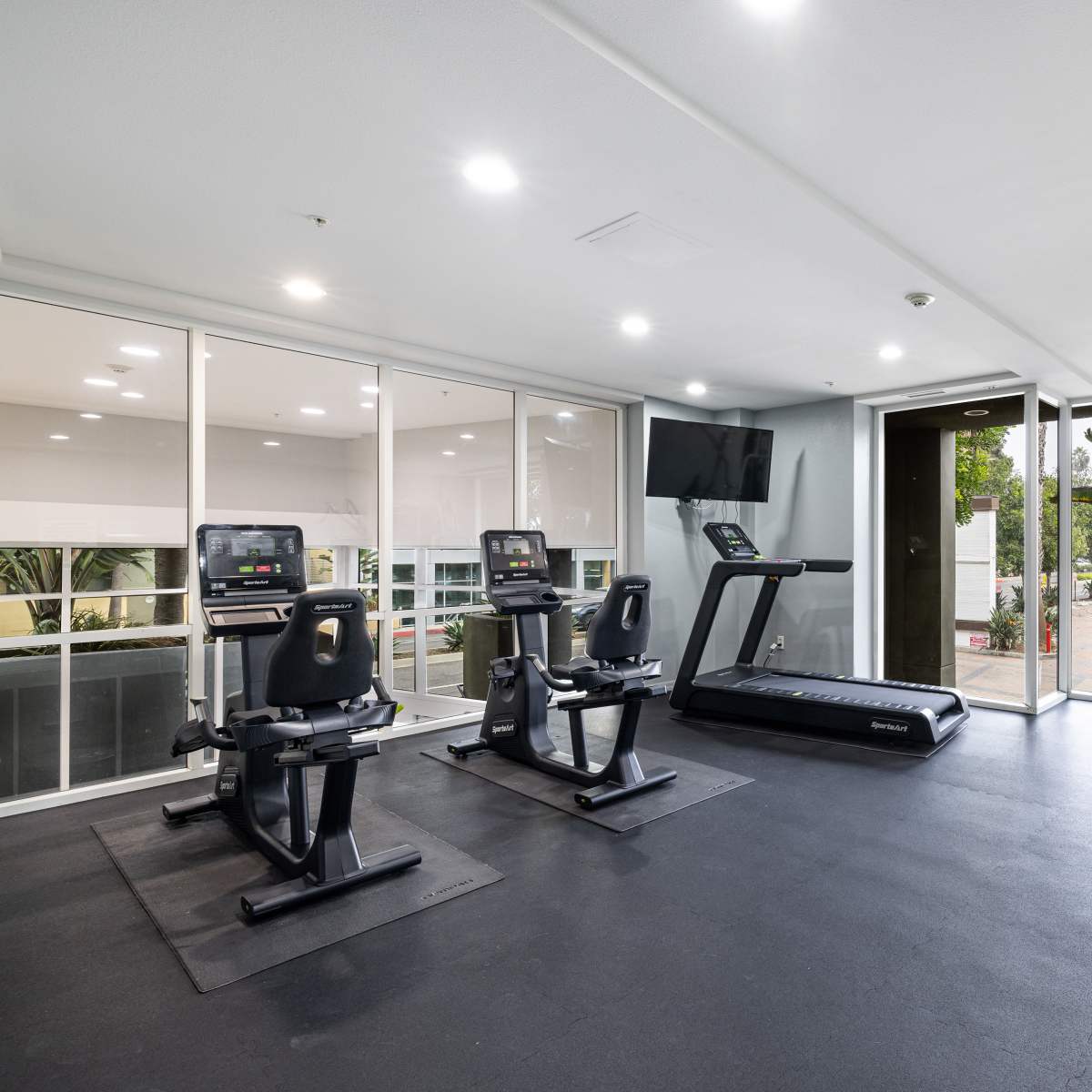 Fitness center with cardio machines and large windows for natural light at Monte Carlo Apartments in Marina Del Rey, California