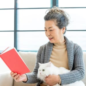 Resident reading and petting her cat in her senior apartment at Sunstone Village in Denton, Texas.