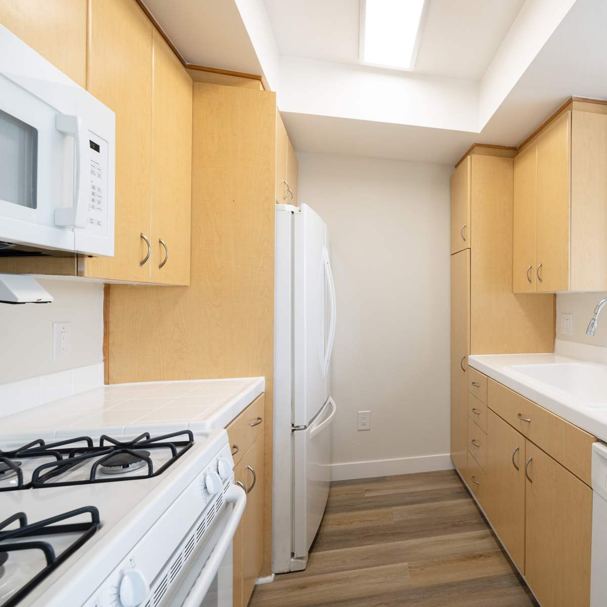Bright kitchen featuring wood-style flooring, stainless steel appliances, and ample cabinetry at Monte Carlo Apartments in Marina Del Rey, California 