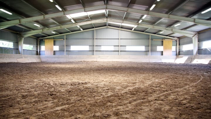 a large empty metal barn with dirt floors | equestrian schools near Keller