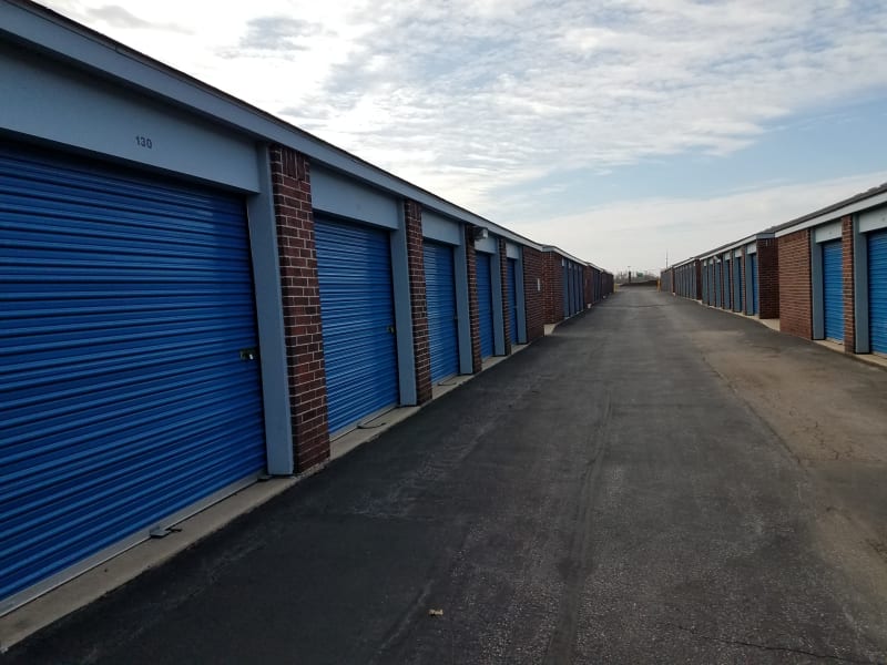 A row of storage units with blue doors and red brick at U-Stor Belton in Belton, Missouri