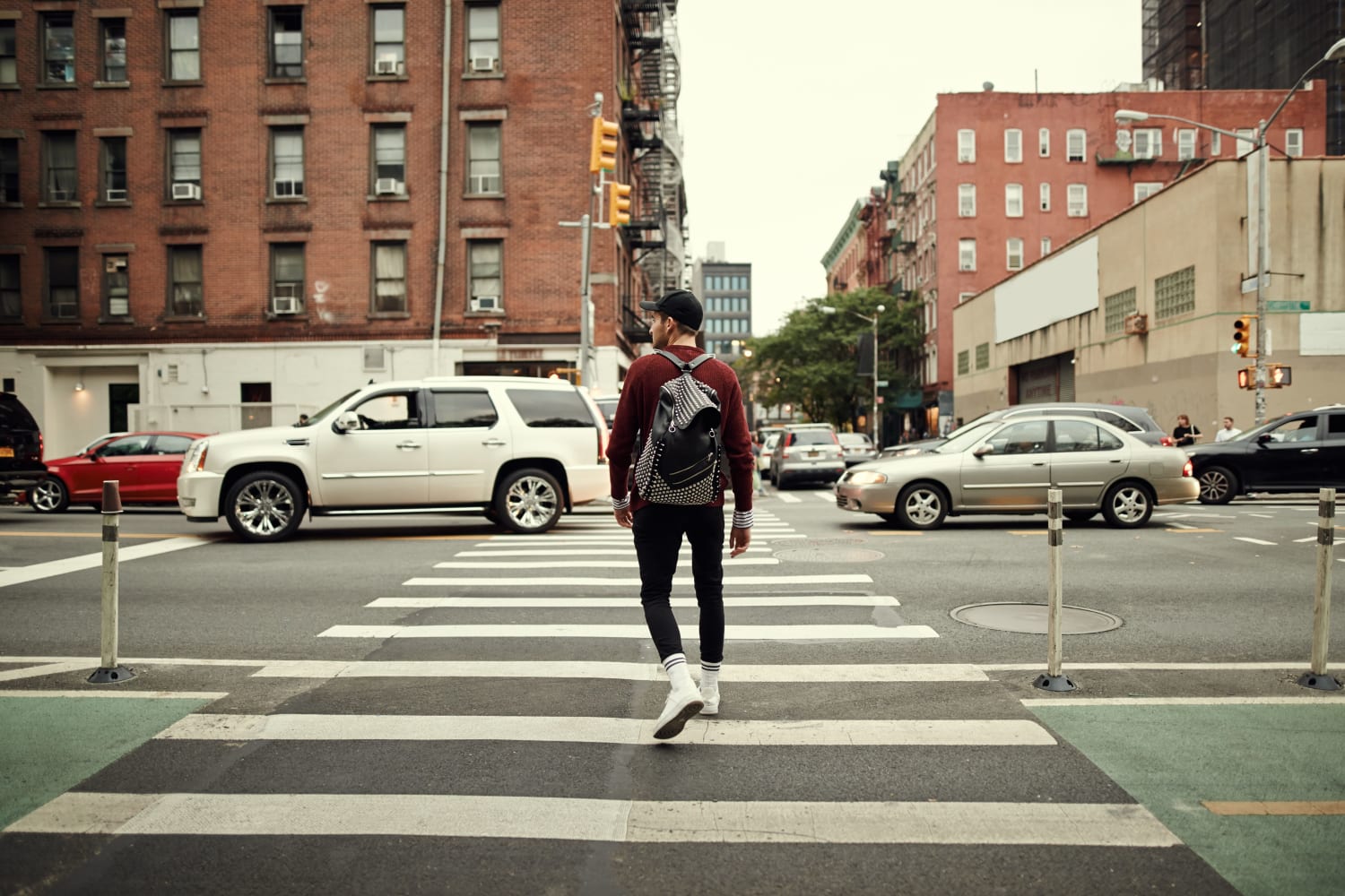 A resident crossing a busy street near 55 Brighton at Packard Crossing in Boston, Massachusetts