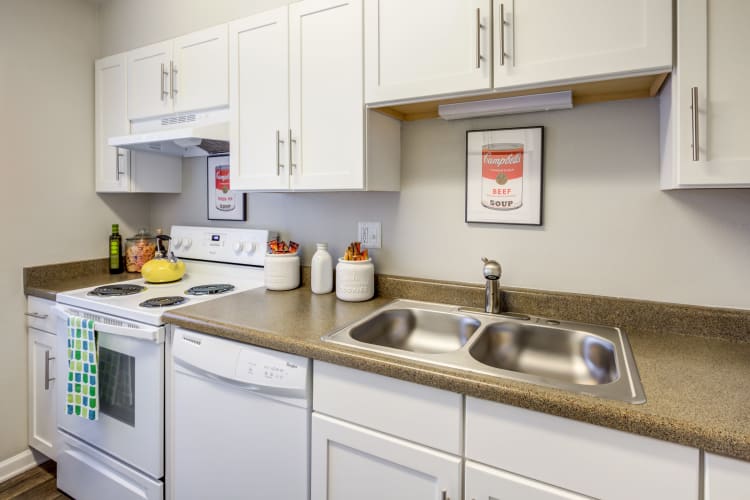 Modern kitchen with bright white appliances and cabinetry in a model home at The Ranch at Bear Creek Apartments & Townhomes in Lakewood, Colorado