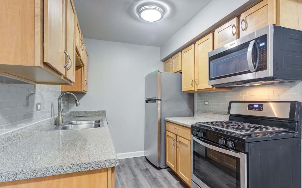 Upgraded kitchen with tile backsplash and stainless steel appliances at The Gates of Deer Grove Apartment Homes in Palatine, Illinois
