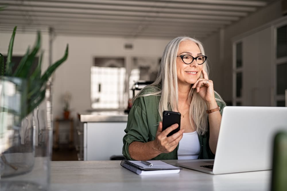 Independent living resident using a laptop in their apartment at Quail Park at Morrison Ranch in Gilbert, Arizona