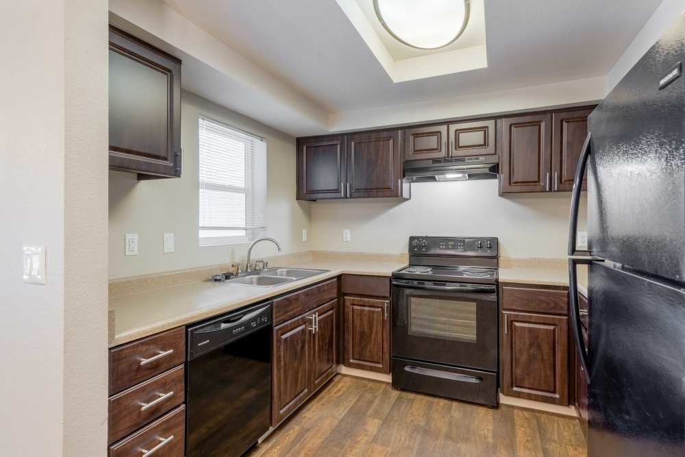 Kitchen with dark wood cabinets and black appliances at The Lodge at McCarran Ranch Apartment Homes in Reno, Nevada
