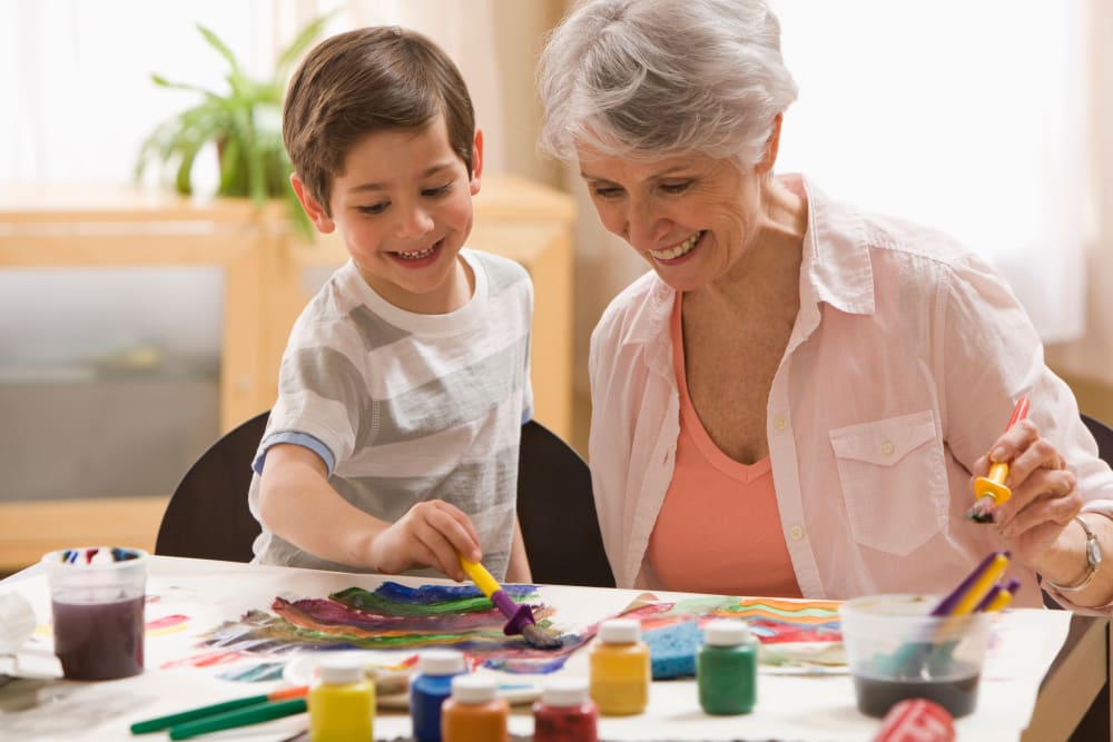 Happy resident painting with grandchild at Merrill Gardens at Columbia in Columbia, South Carolina