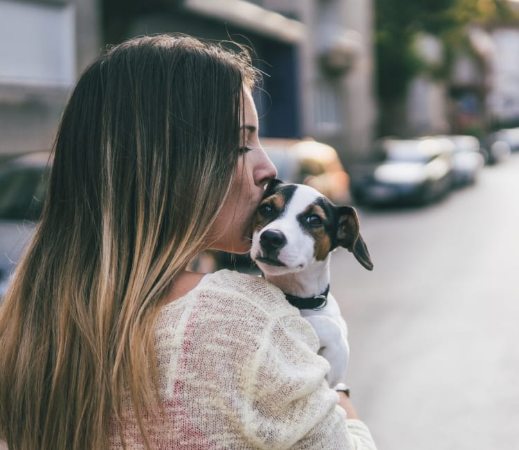 Resident giving her puppy a kiss outside their new home at Sofi Belmont Glen in Belmont, California