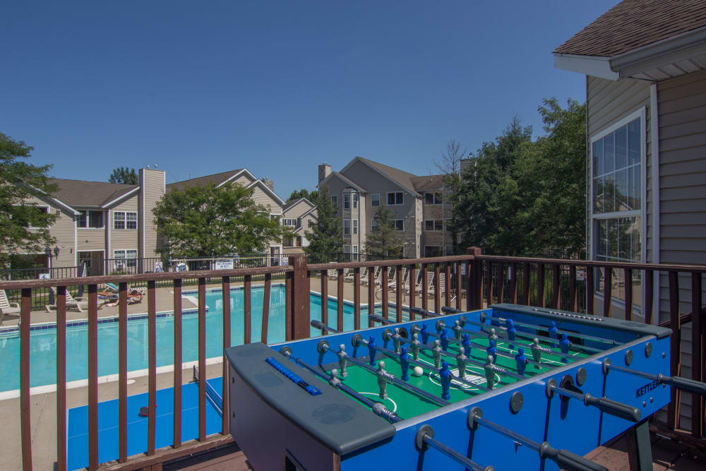 Foosball table next to a pool on under a blue clear sky in the apartment complex located at Hills of Aberdeen Apartment Homes in Valparaiso, Indiana