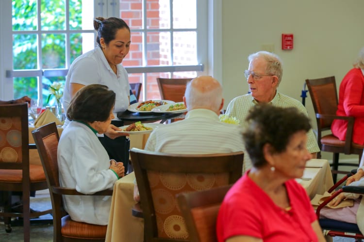 Residents being served dinner in the dining room at The Harmony Collection at Columbia Assisted Living & Memory Care in Columbia, South Carolina