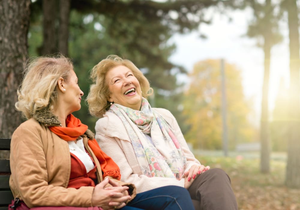 Residents sitting on a bench outside of Autumn Grove Cottage at Stone Oak in San Antonio, Texas