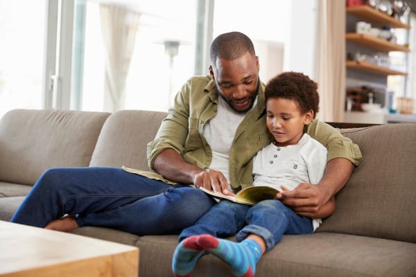 Father and son on their couch at Applewood Apartments in DeLand, Florida