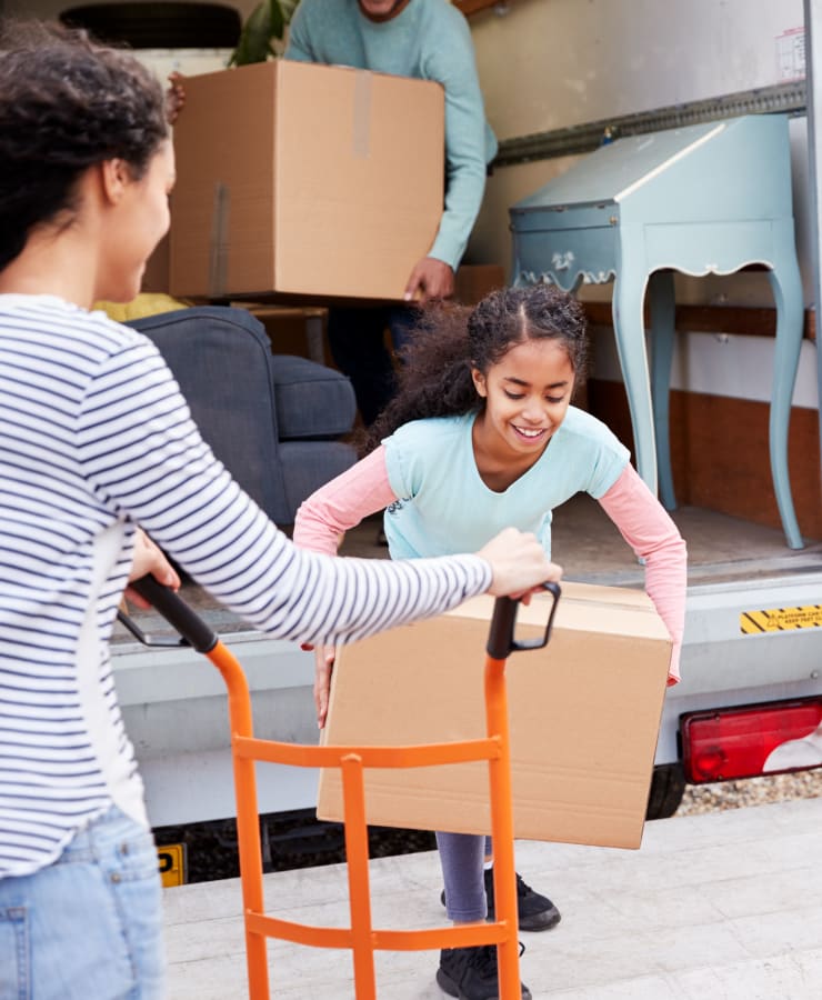 A smiling child helps to unpack a moving truck near Seaport Storage in Tampa, Florida