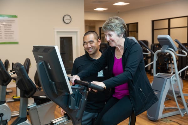 A caretaker assisting a resident with an exercise machine at Touchmark at Fairway Village in Vancouver, Washington