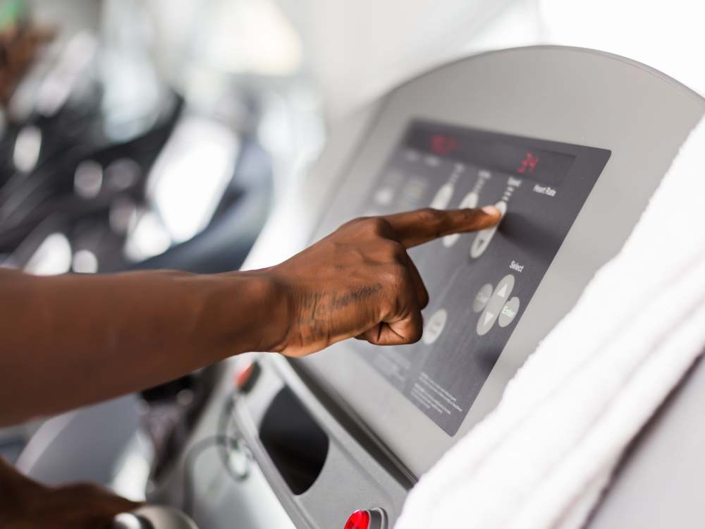Person adjusting settings on a treadmill in a bright gym environment at 43 North Apartments in Grand Haven, Michigan