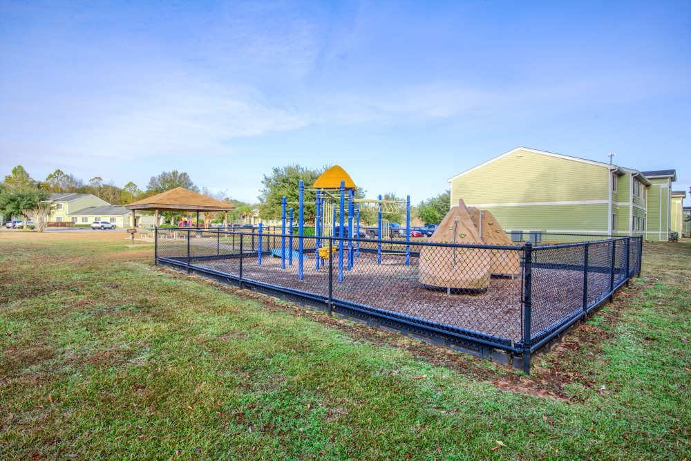 Playground area with swings, climbing structures, and shaded picnic pavilion in a gated community setting at Magnolia Crossing and Bell Ridge II in Pace, Florida