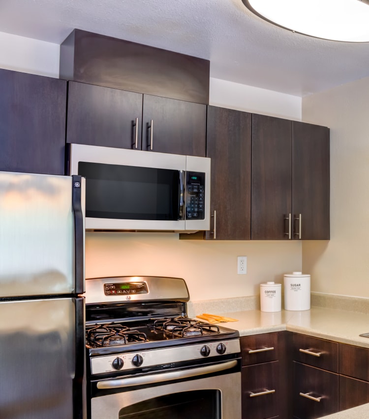 Stainless-steel appliances and rich, dark wood cabinetry in a model home's kitchen at Sofi Belmont Hills in Belmont, California