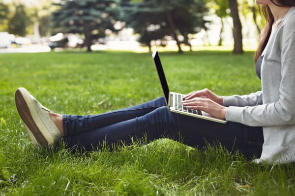 A lady working on her computer in the grass at The Emerson at Forney Marketplace in Forney, Texas