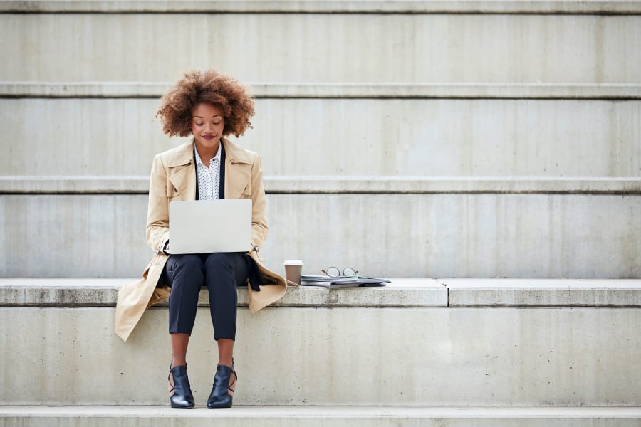 Resident working on her laptop on the steps outside her office near Sofi Warner Center in Woodland Hills, California