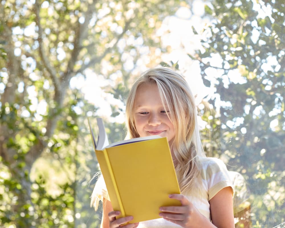 Resident child reading a book outside her new home on another beautiful day at Sofi Canyon Hills in San Diego, California