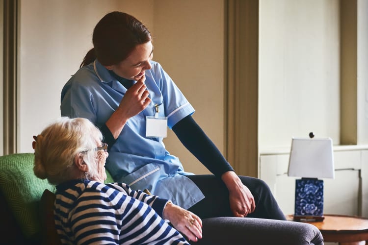 A resident and caretaker sitting and laughing together at Harmony Senior Services in Charleston, South Carolina
