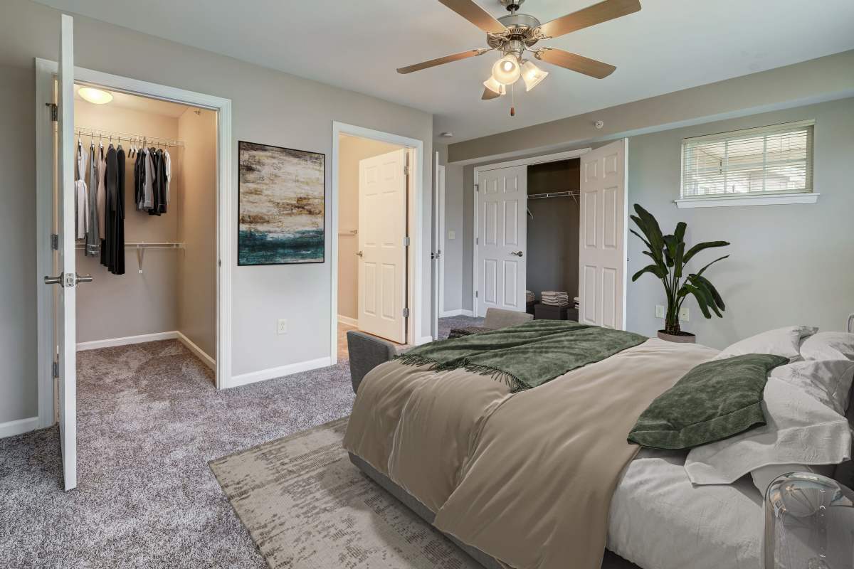 Staged bedroom with wall to wall carpeting, 2 closets, and attached bath at Webster Green in Webster, New York