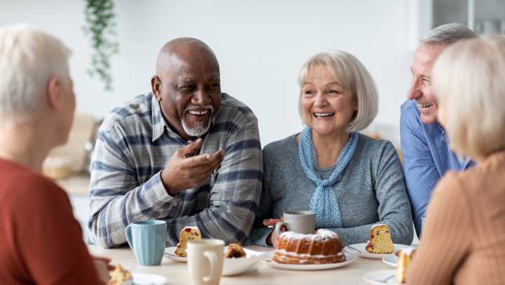Elderly individuals around a table smiling and chatting.