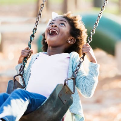 A child playing on the swings on a playground at Discovery Village in Joint Base Lewis McChord, Washington