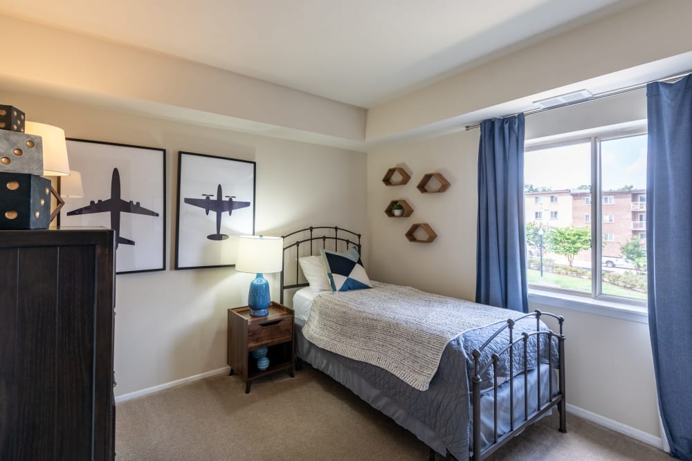 Staged bedroom with twin bed, nightstand, and dresser at The Willows Apartment Homes in Glen Burnie, Maryland