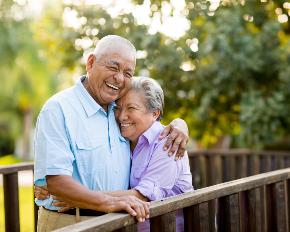 Resident couple hugging while standing on a bridge outside near Edencrest at Beaverdale in Des Moines, Iowa.