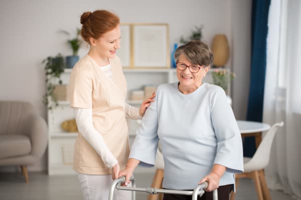 A caretaker assisting a resident with her walker at Harmony Senior Services in Charleston, South Carolina